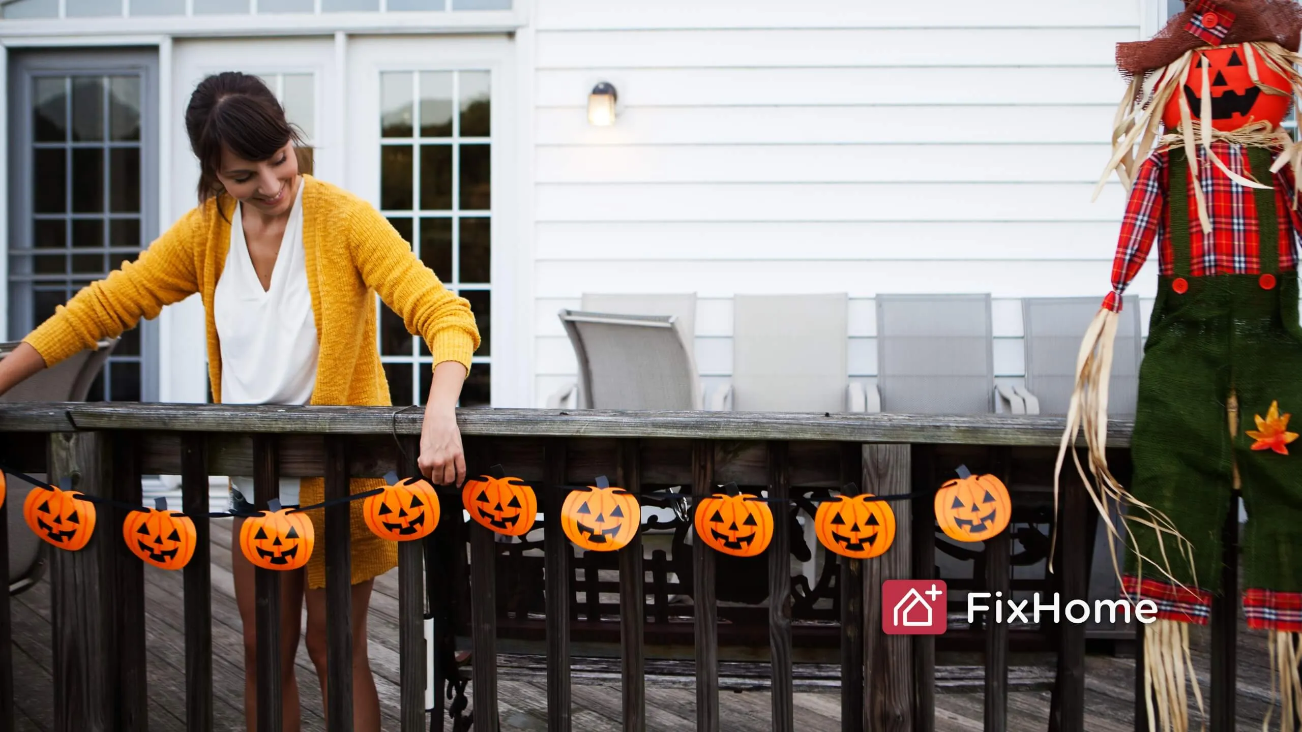 Woman hanging Halloween decor on the deck fence