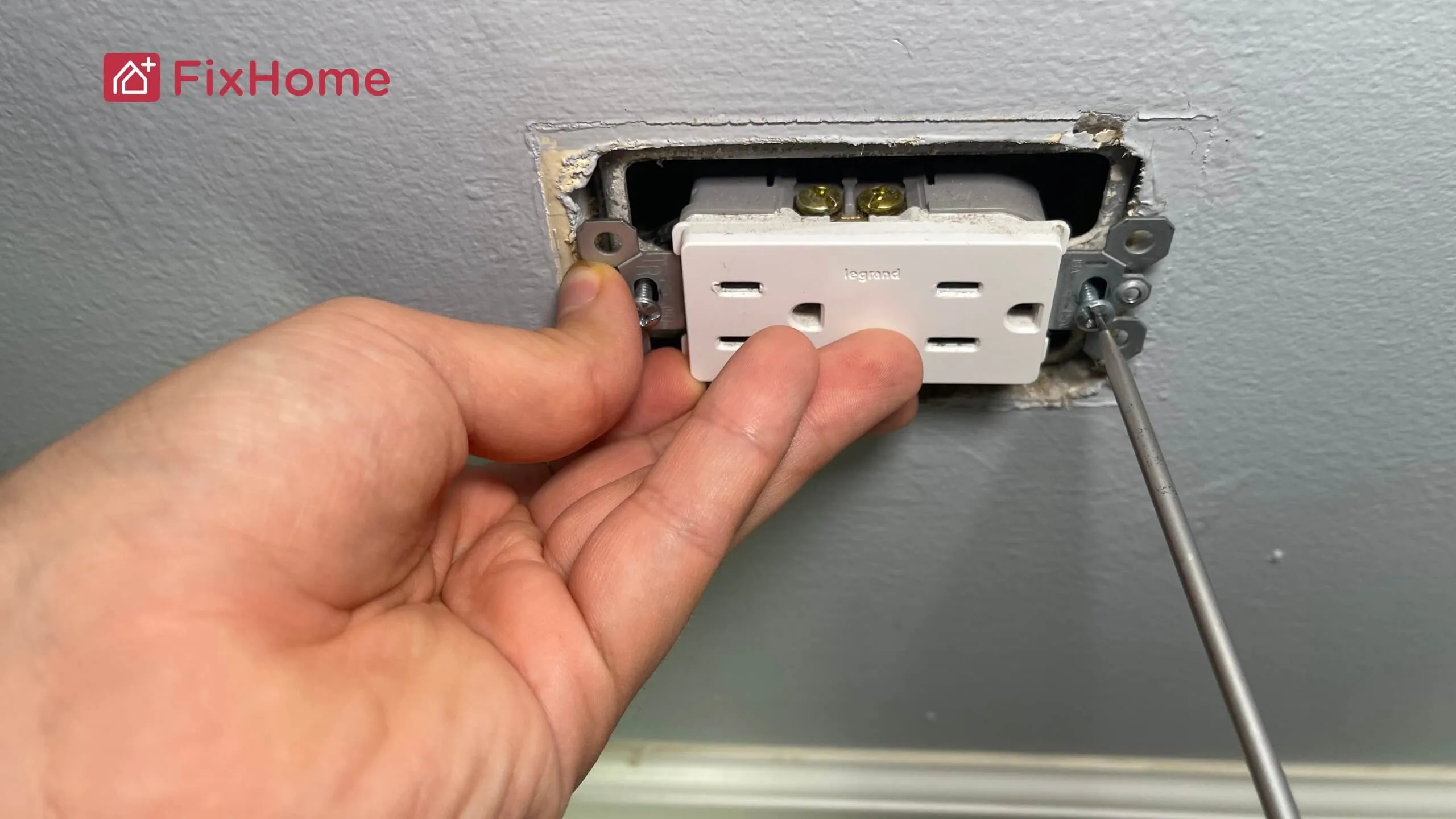 A person replacing an old wall outlet with a new one.