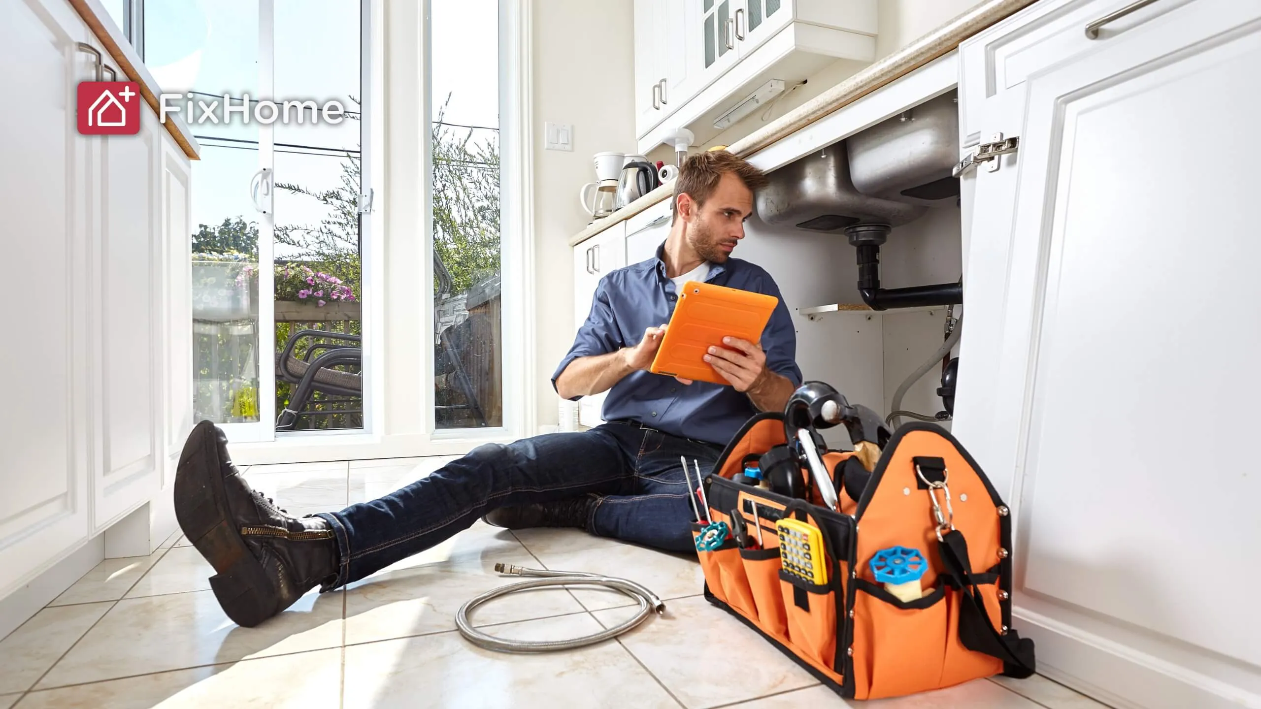 Handyman sitting on the kitchen floor resolving pipe problems