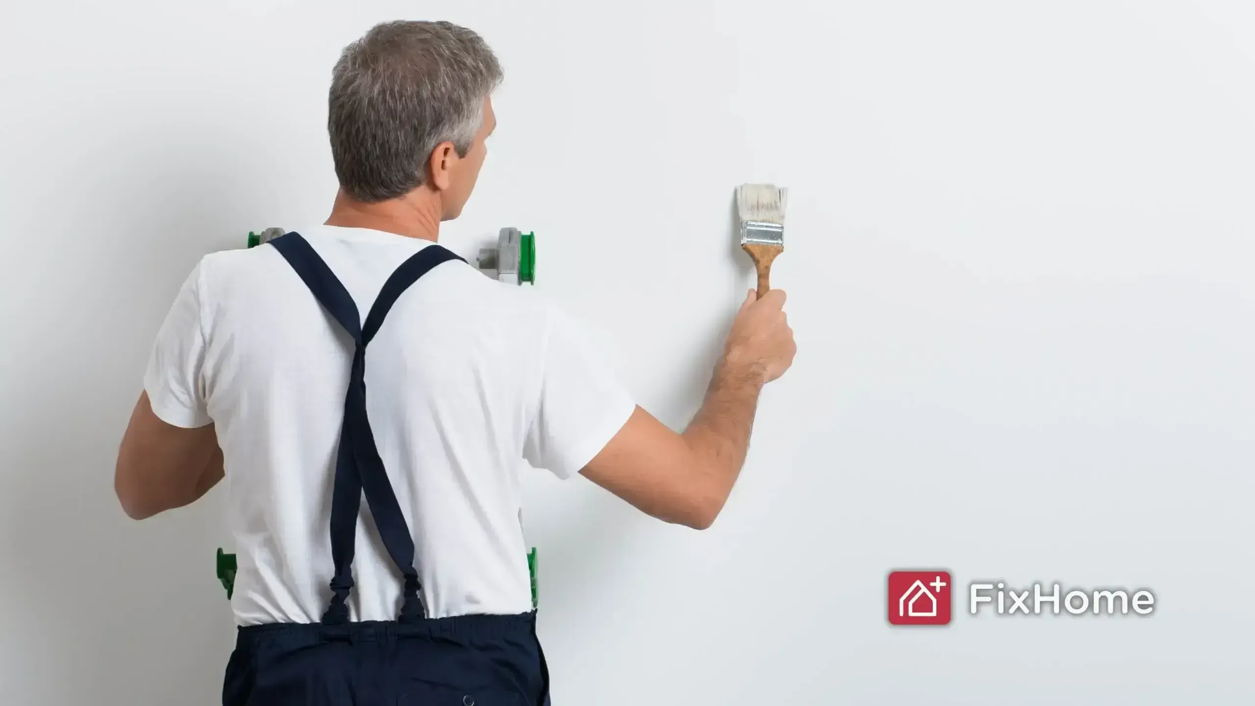 Painter in white shirt and suspenders painting a plain white wall