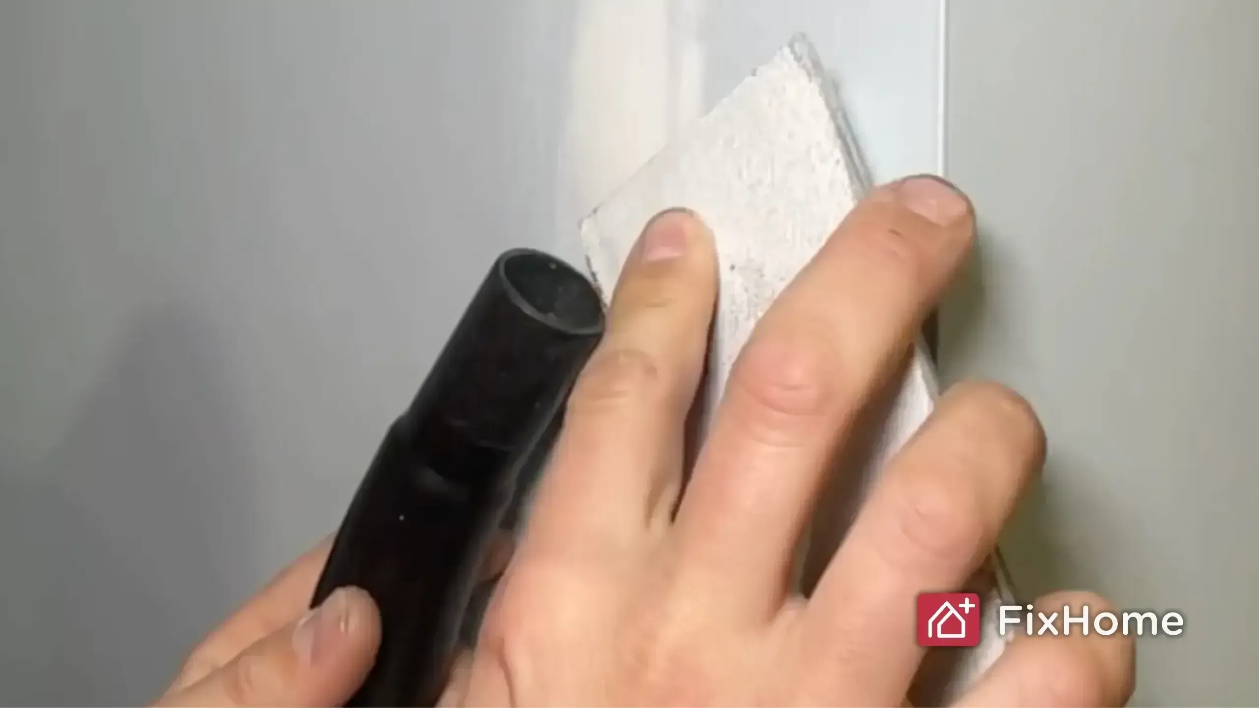 Sanding a wall with a vacuum nozzle nearby