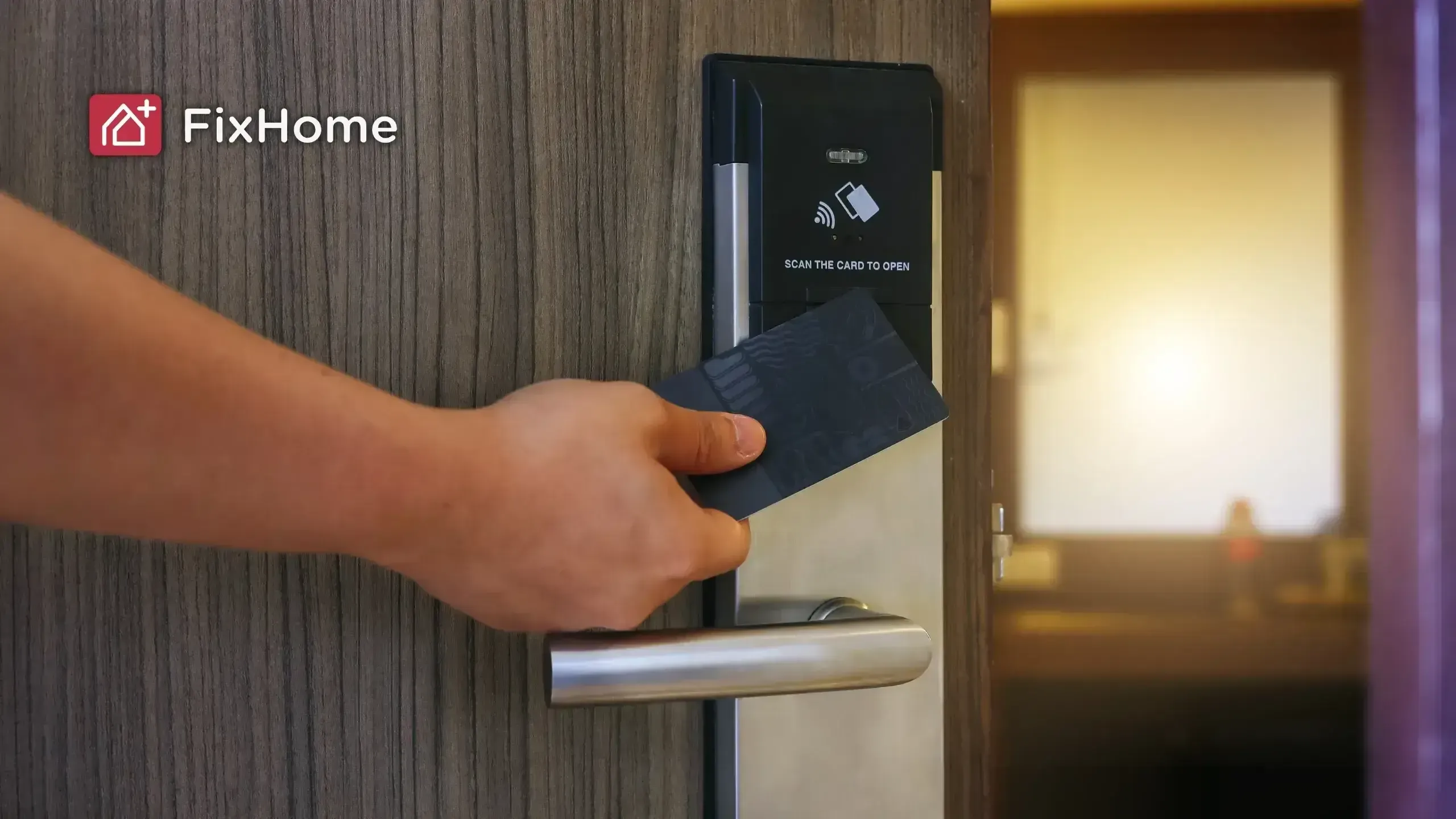 Hand holding a black card near a smart door lock with a card reader panel, mounted on a wooden door