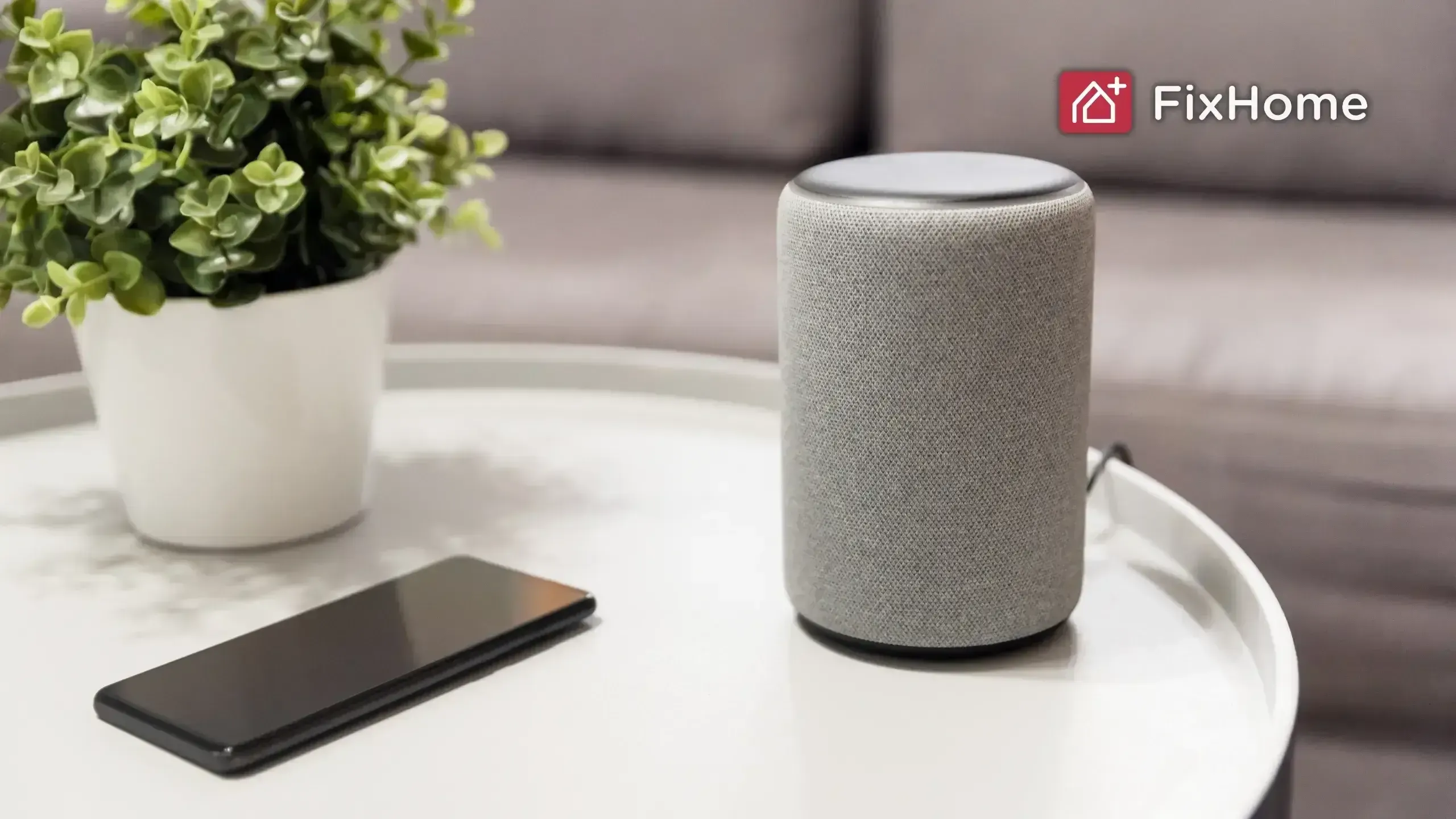 Smart speaker, smartphone, and potted plant arranged on a round white table in a modern living room