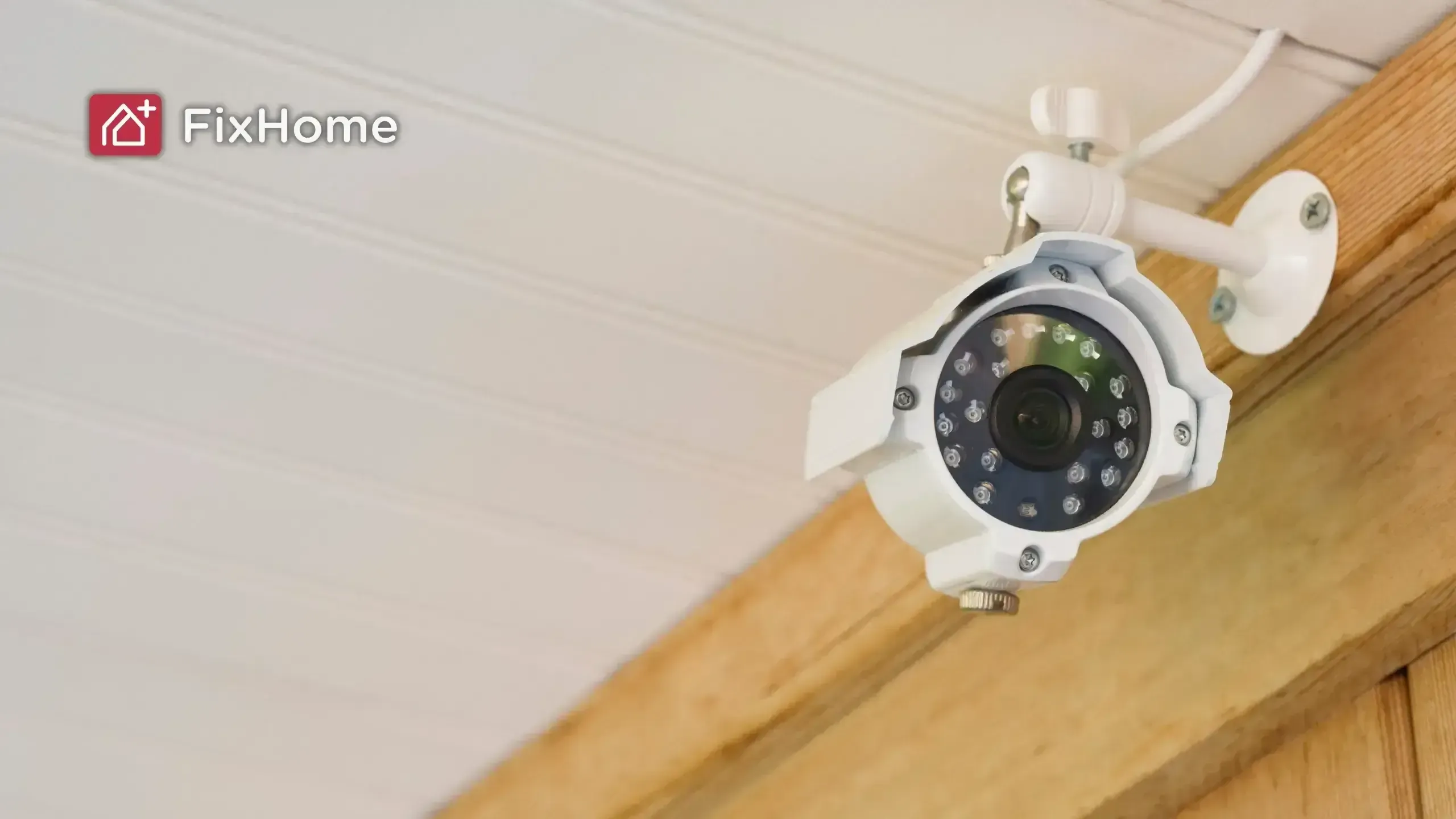 White security camera mounted on a ceiling with wooden trim