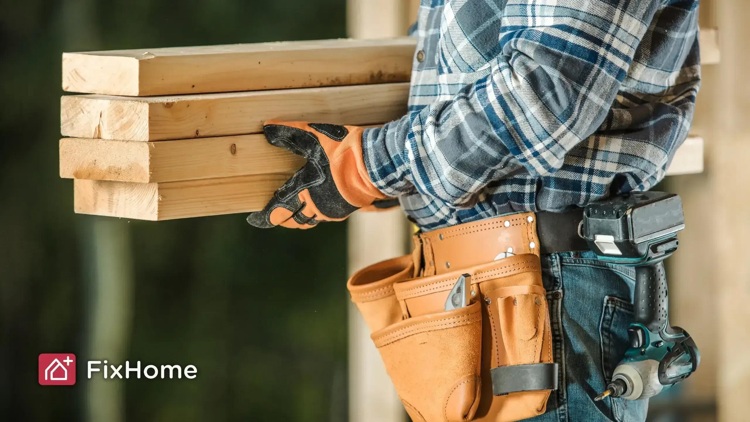 A construction worker holding wooden planks, wearing a tool belt and gloves