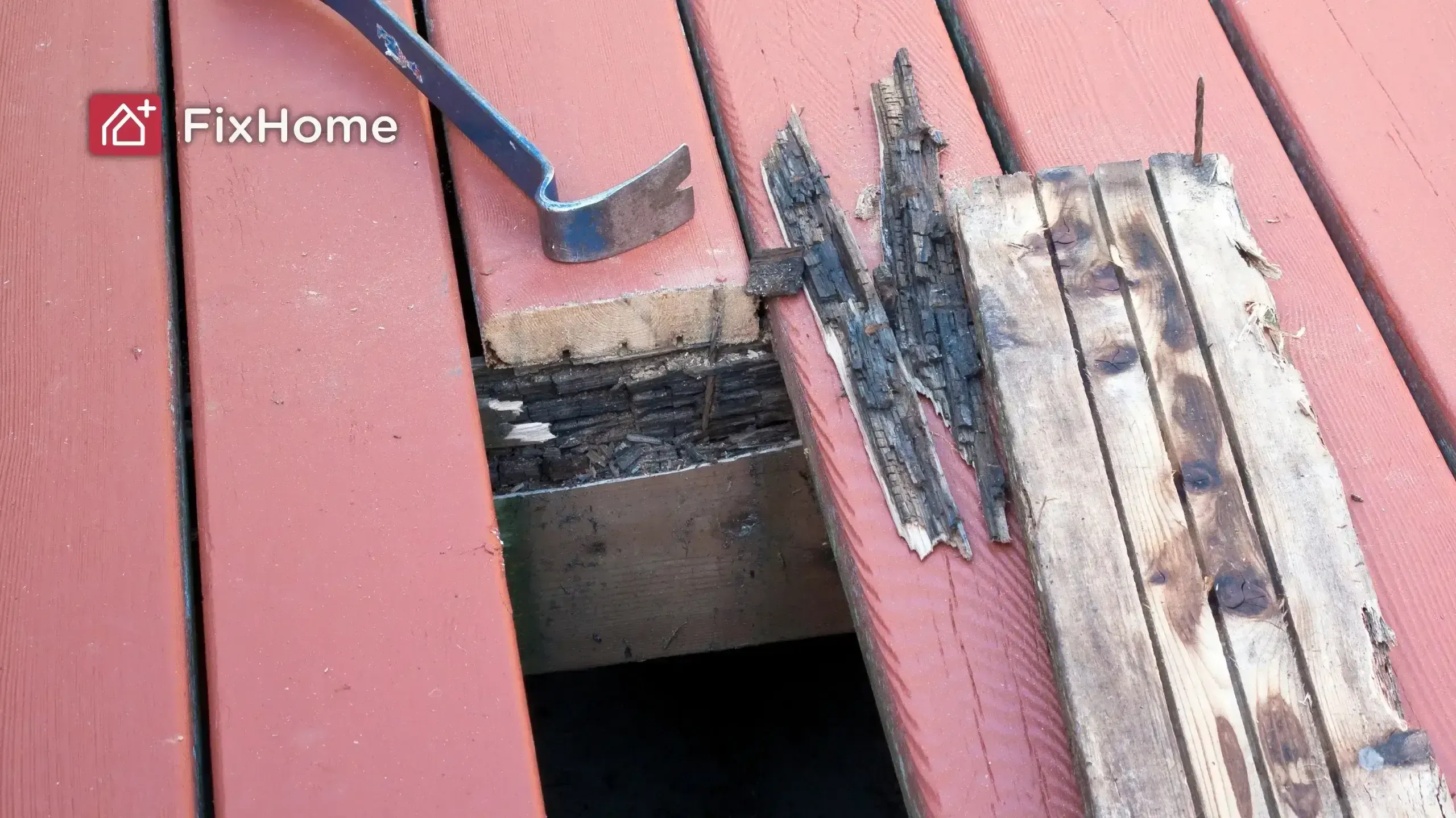 Damaged wooden deck boards with a pry bar, exposing rotten wood underneath.
