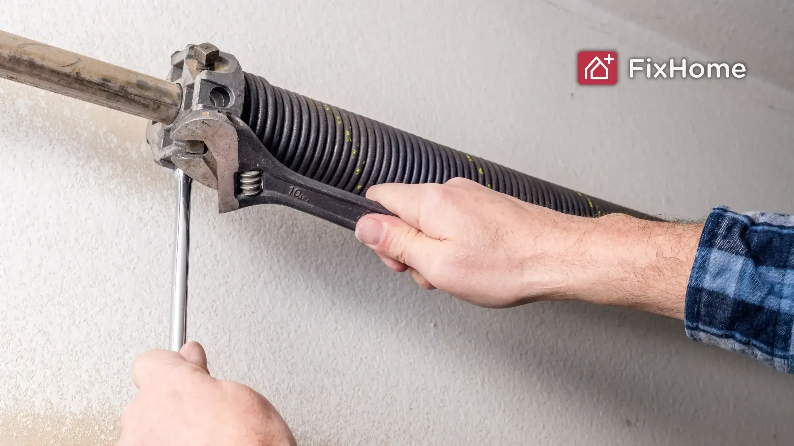 A handyman is tightening a garage door spring using a wrench and a tool in a home setting