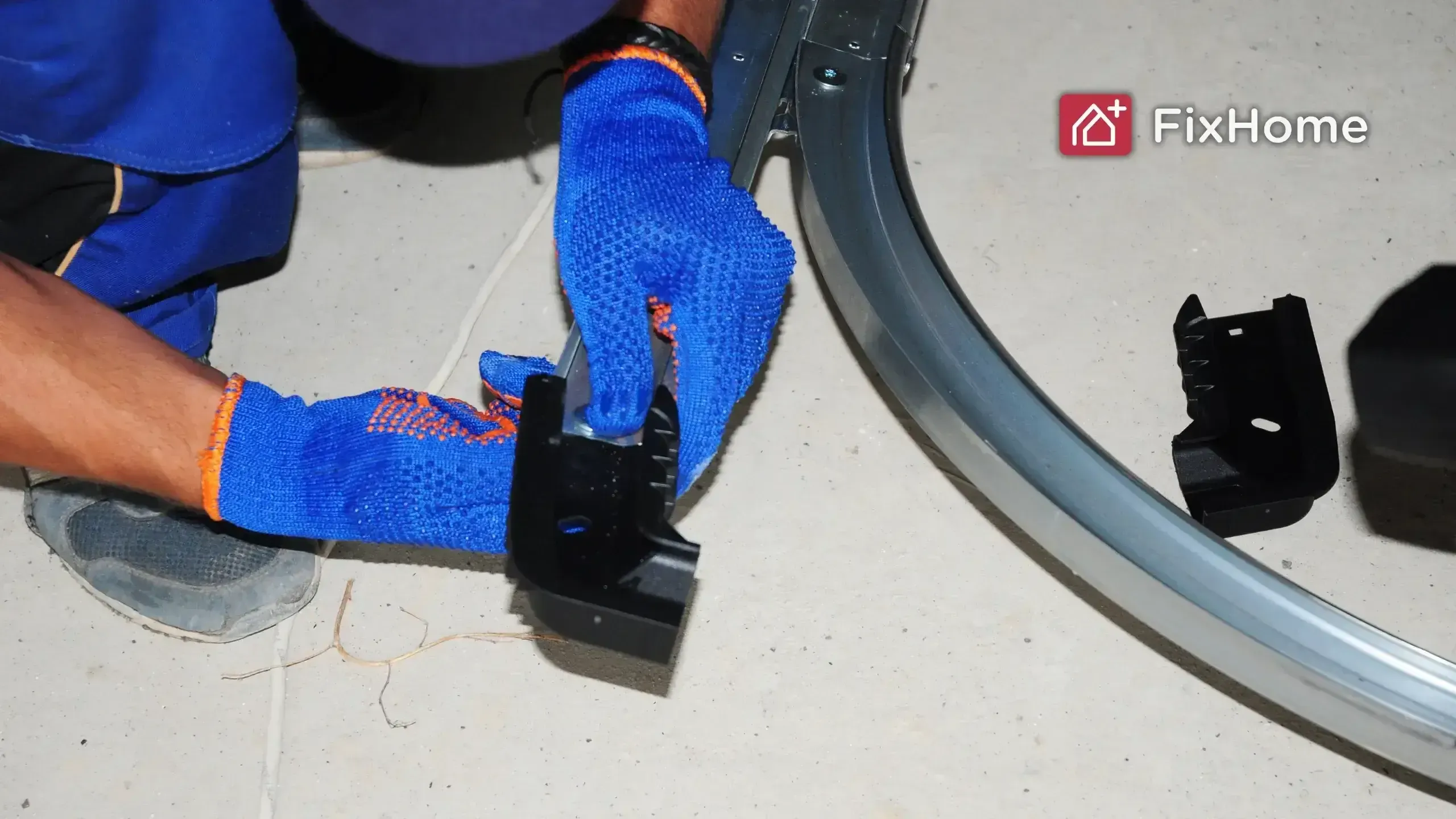 A garage door repairman in blue gloves is repairing a garage door spring with a metal frame on the ground