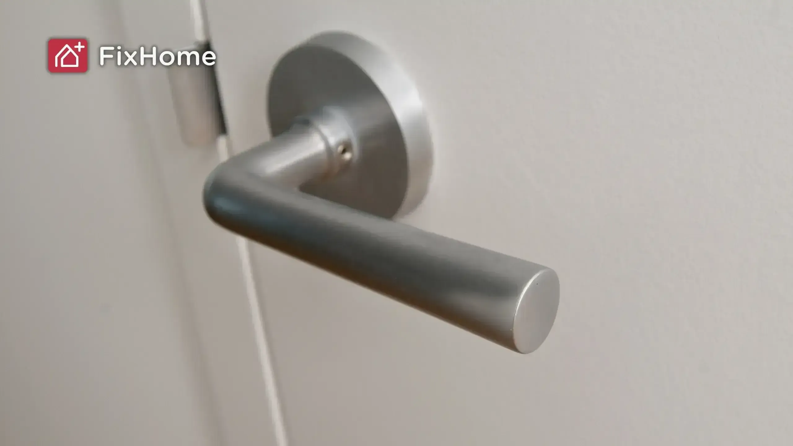 A silver lever door handle mounted on a white door