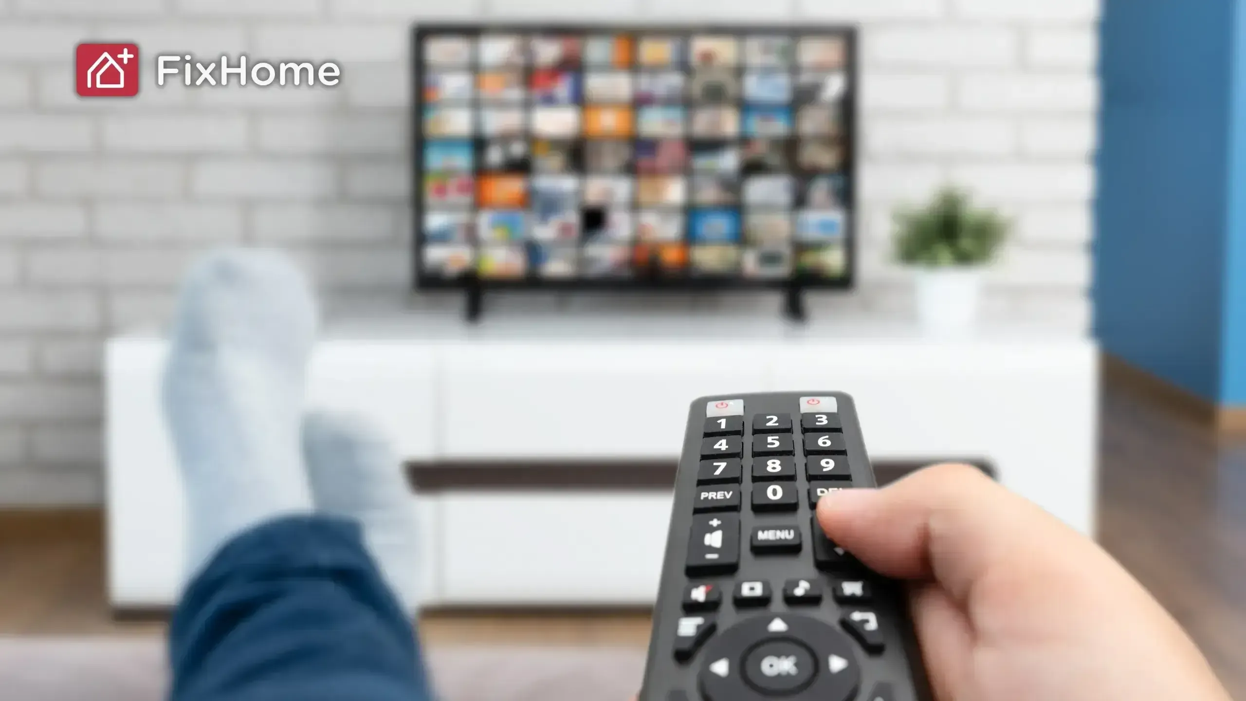 A person with TV remote and a smart tv on the white stand