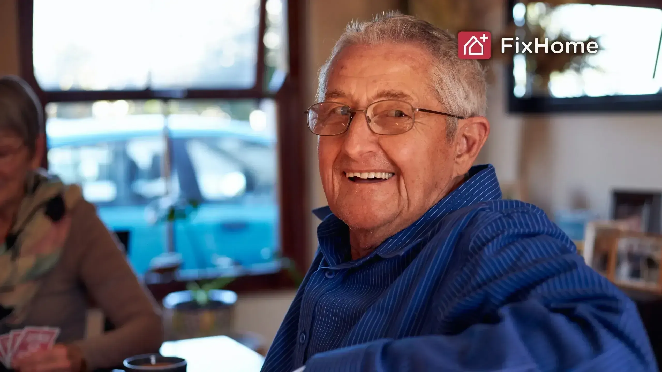 A smiling senior sitting at a table with a cup of coffee