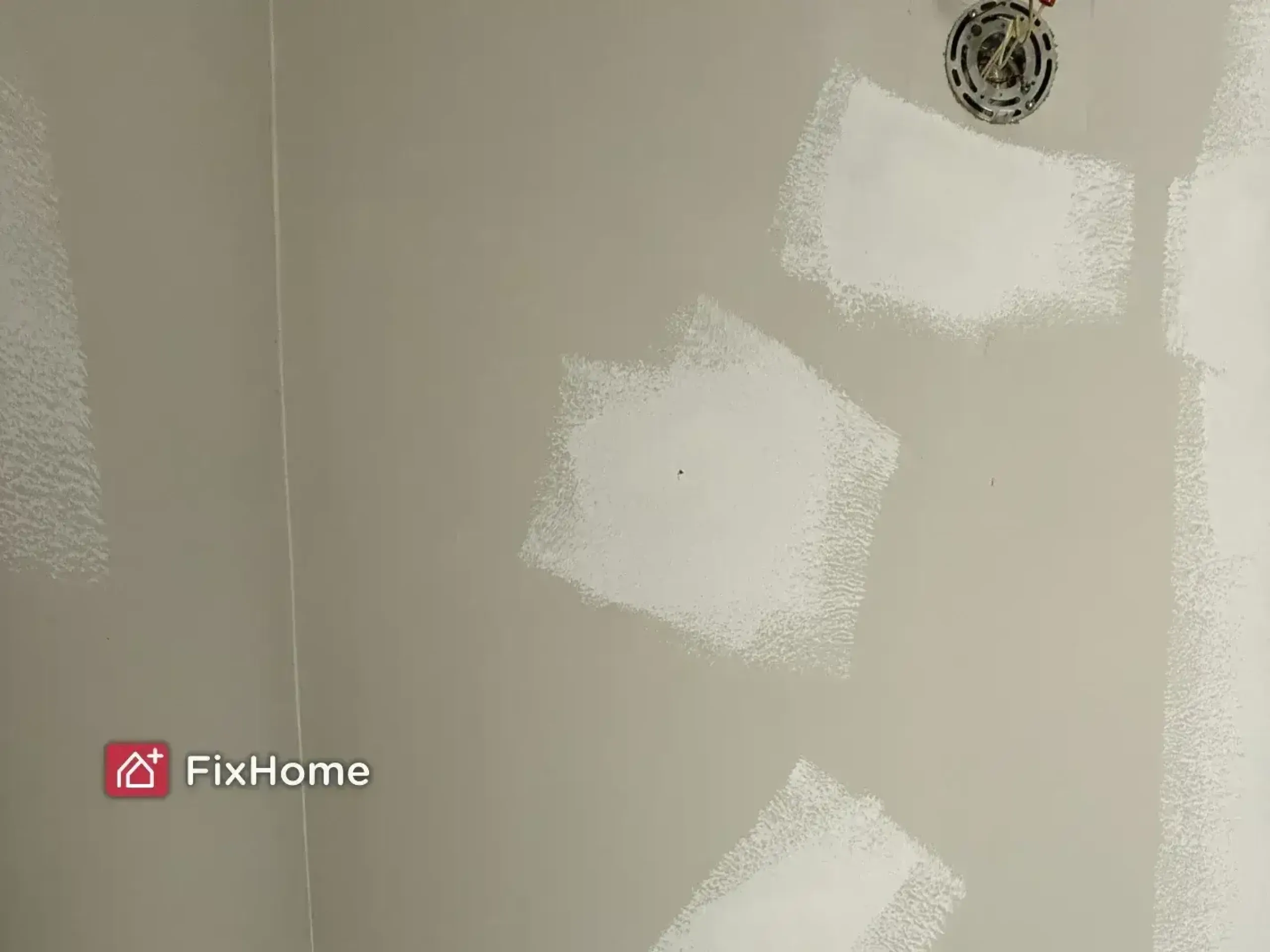 A bathroom wall with several white patches, showing spots of unfinished paint work