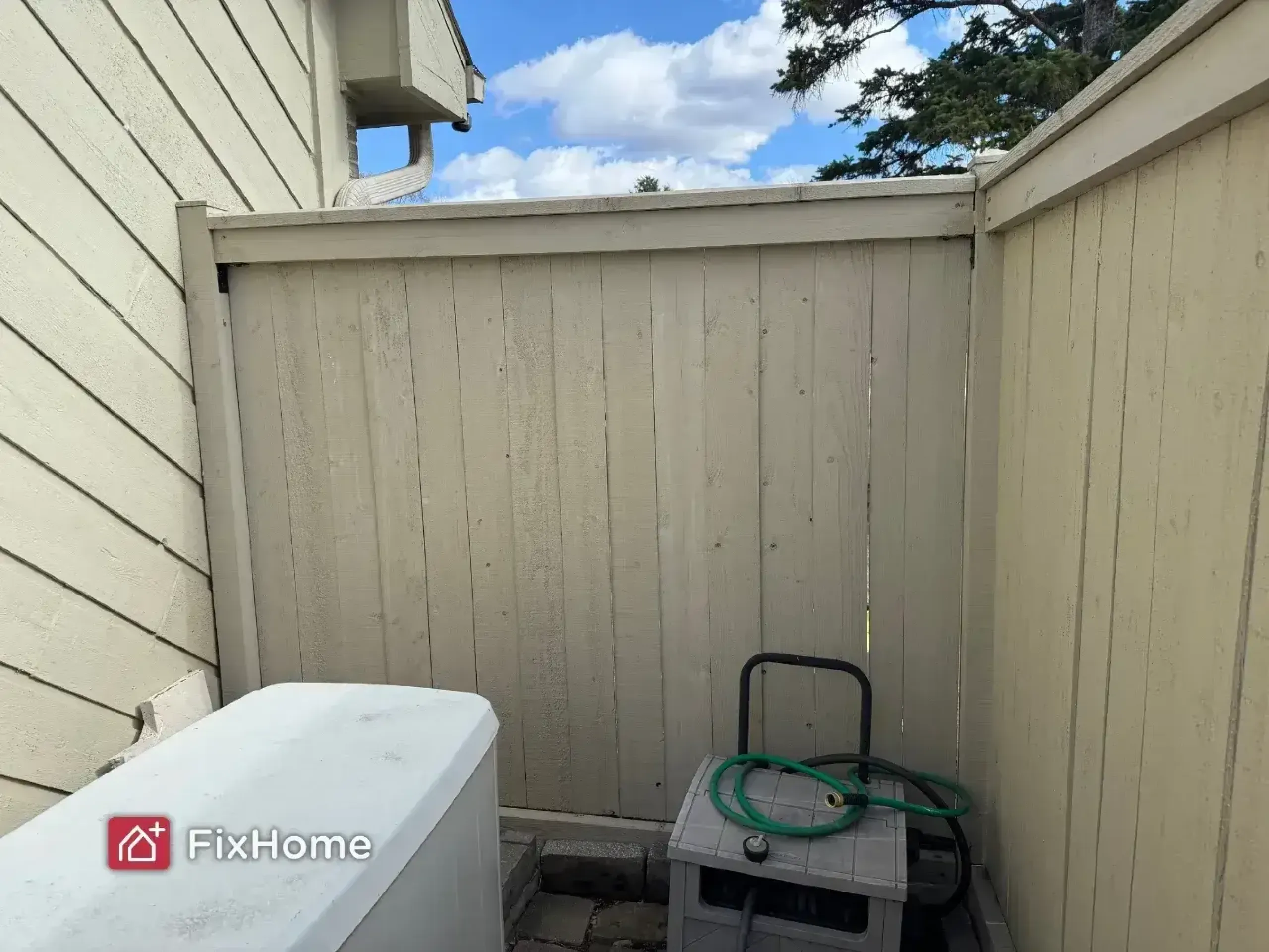 A fixed fenced outdoor area with a generator and a gray box with a green hose