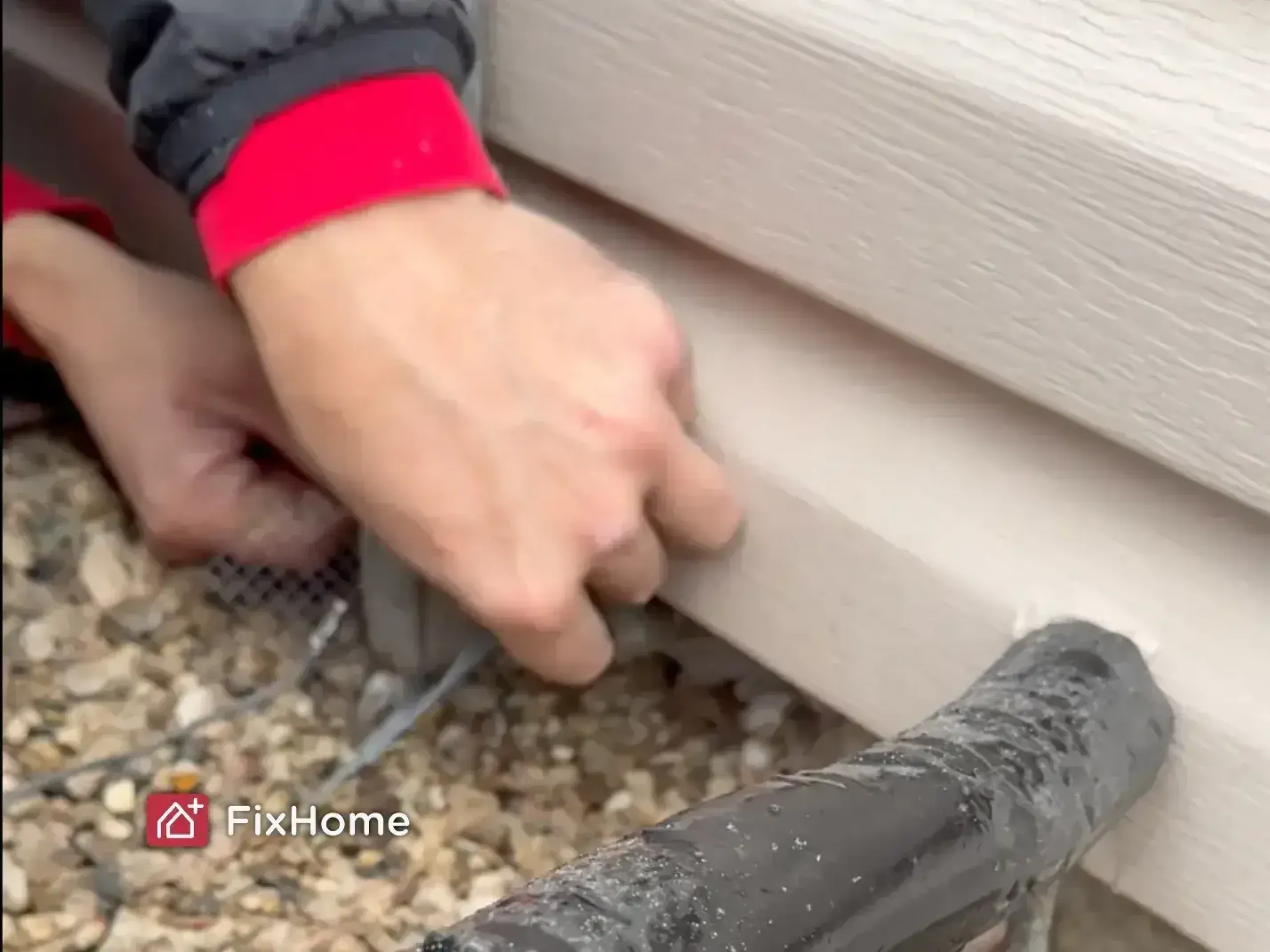 Person securing galvanized hardware cloth near the house foundation