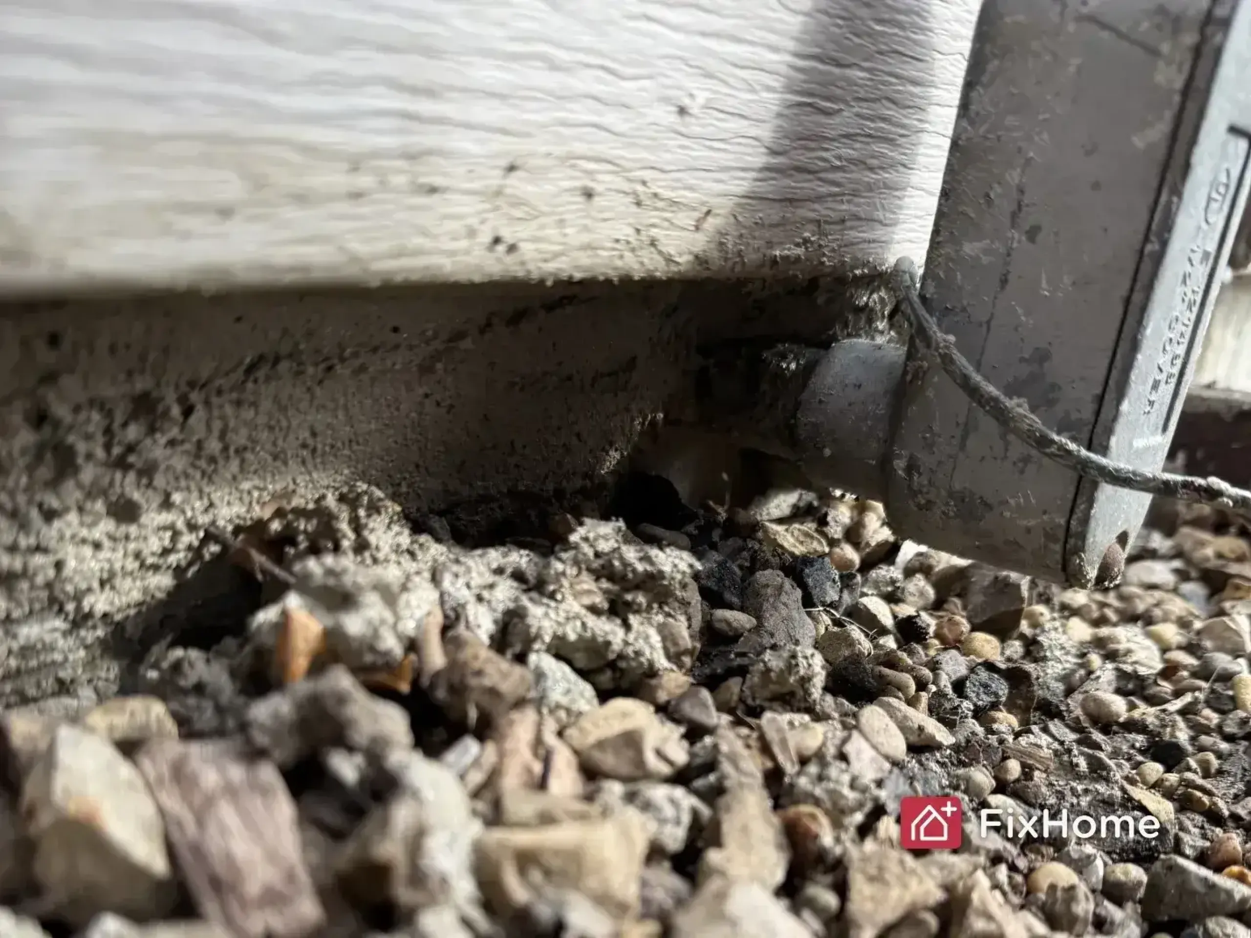 Gap near the base of a house is being filled to stop pests from entering