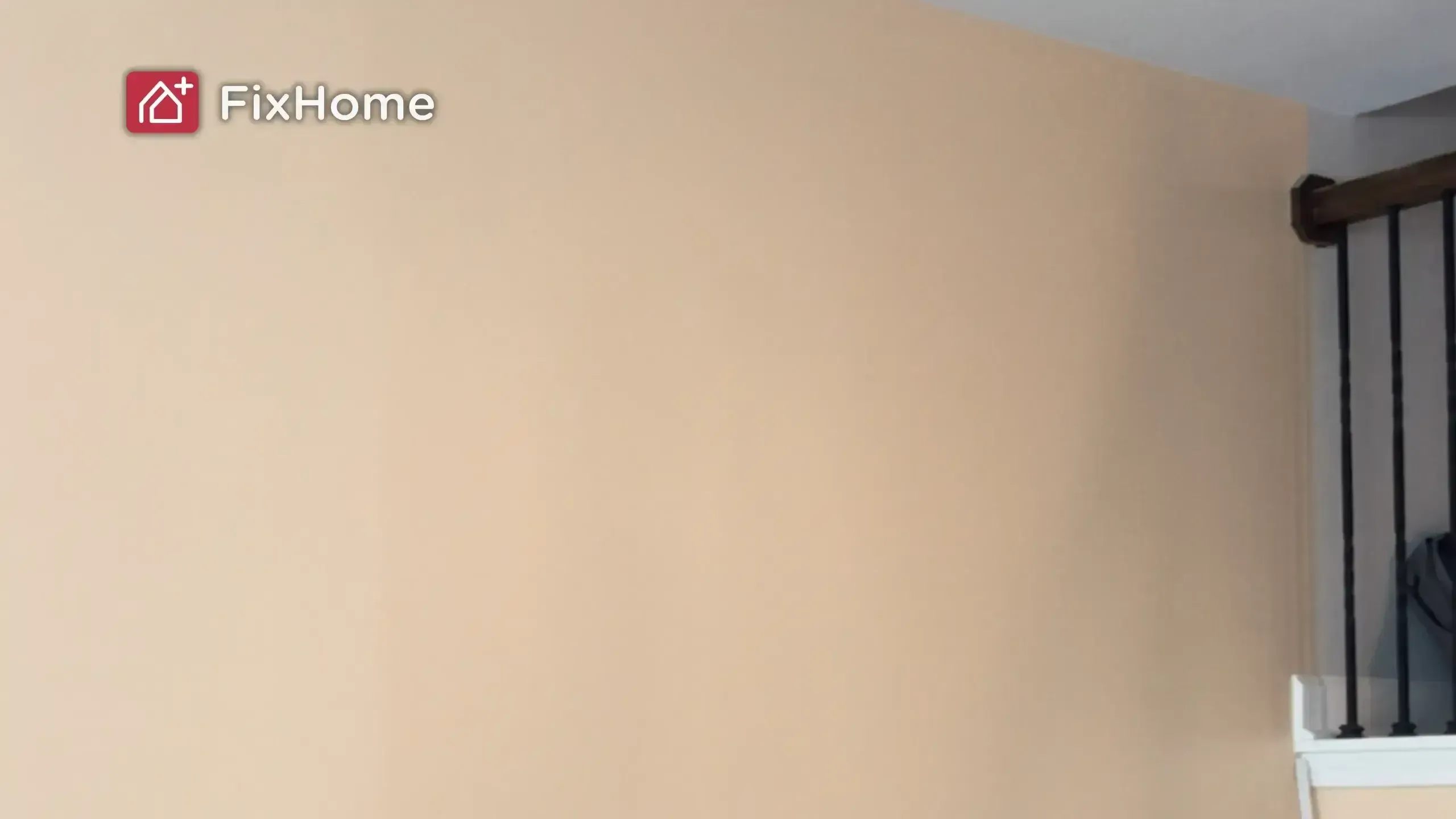 A light beige wall with a wooden railing in the corner.