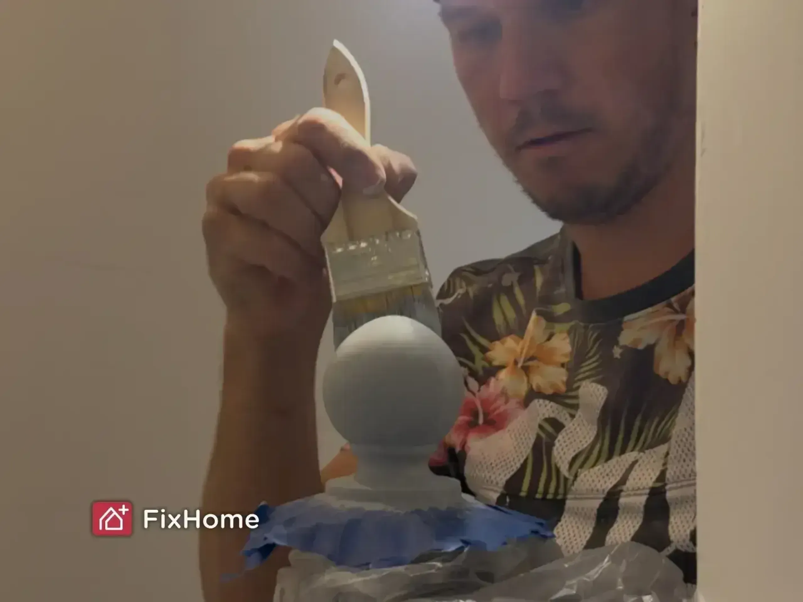 Handyman painting a decorative wooden finial with a brush, appearing focused.