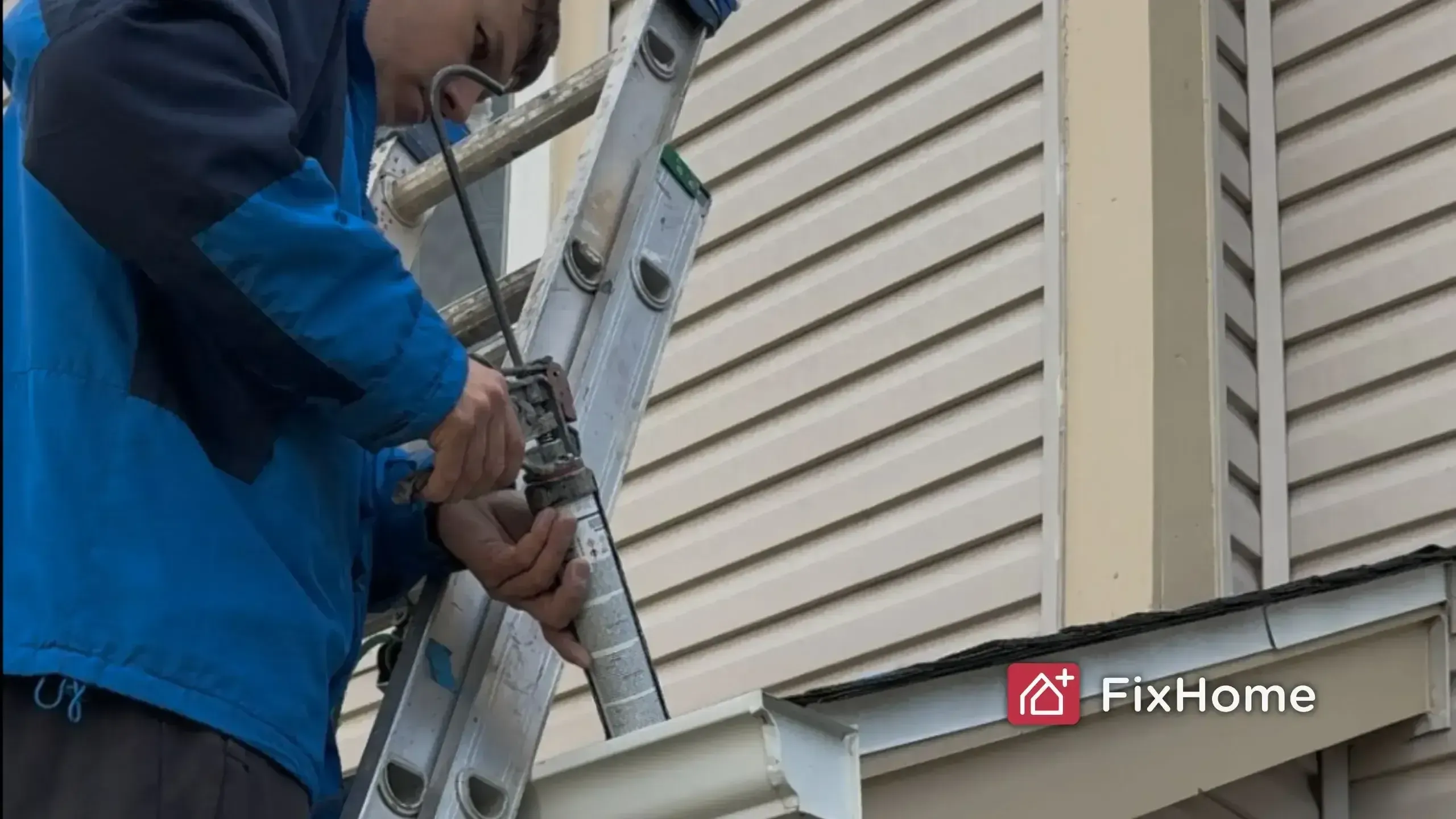 Handyman sealing a rain gutter downspout connection on a ladder