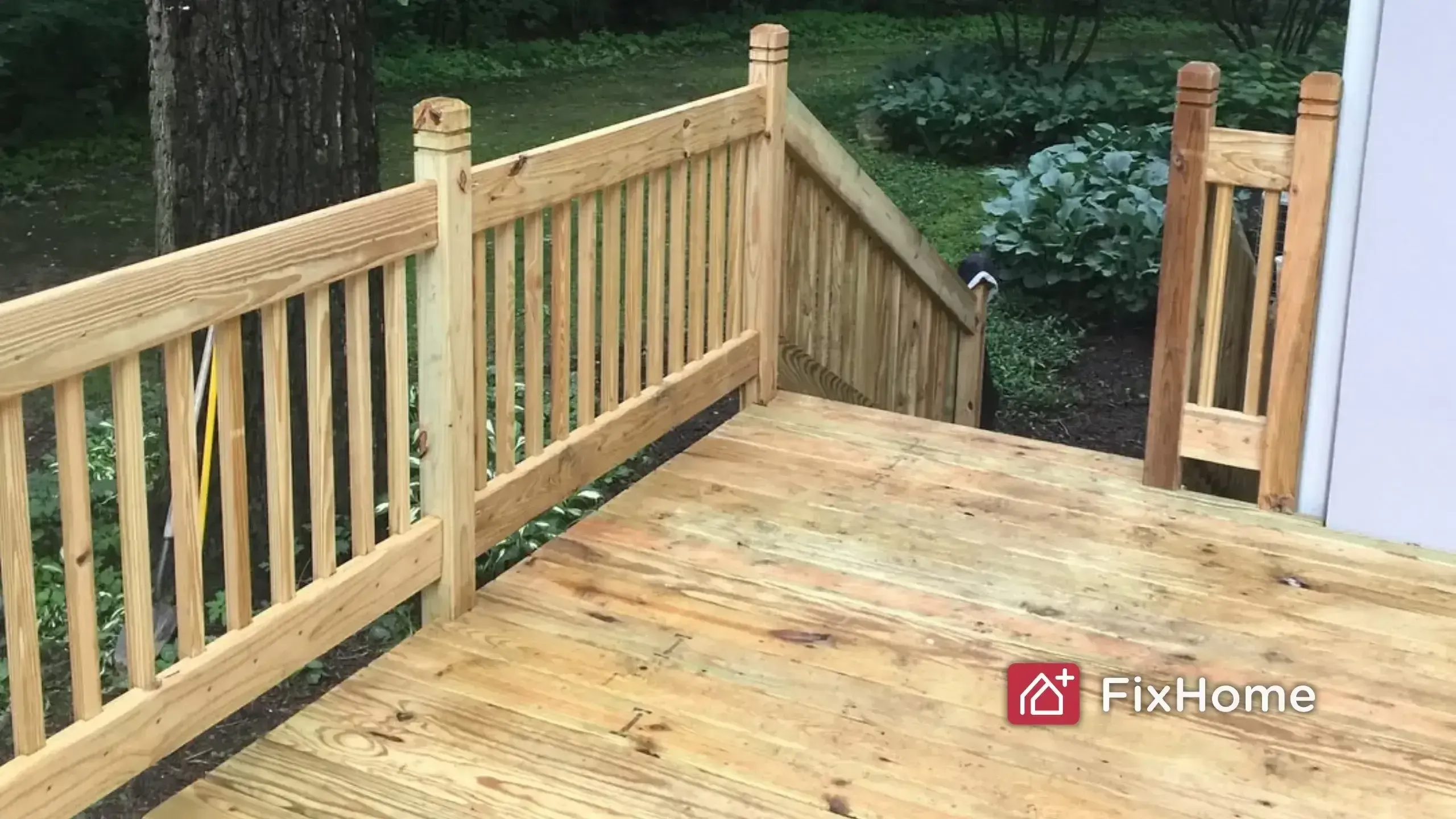 A brand new pressure-treated wood deck with railings in a suburban backyard