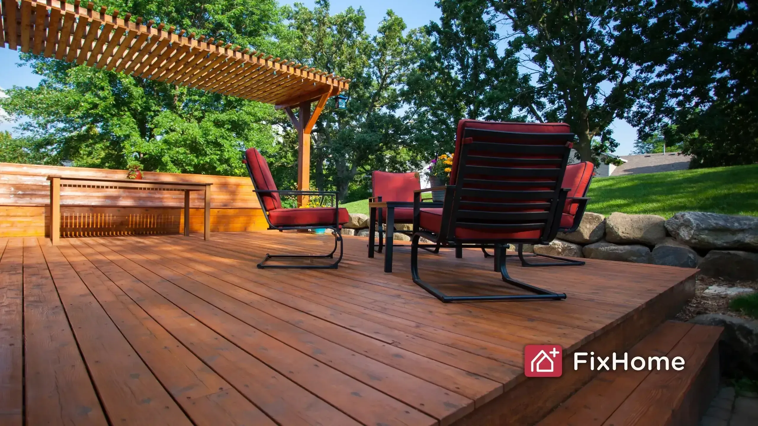 Wood deck with semi-transparent stain showing natural grain, patio chairs, and pergola in background