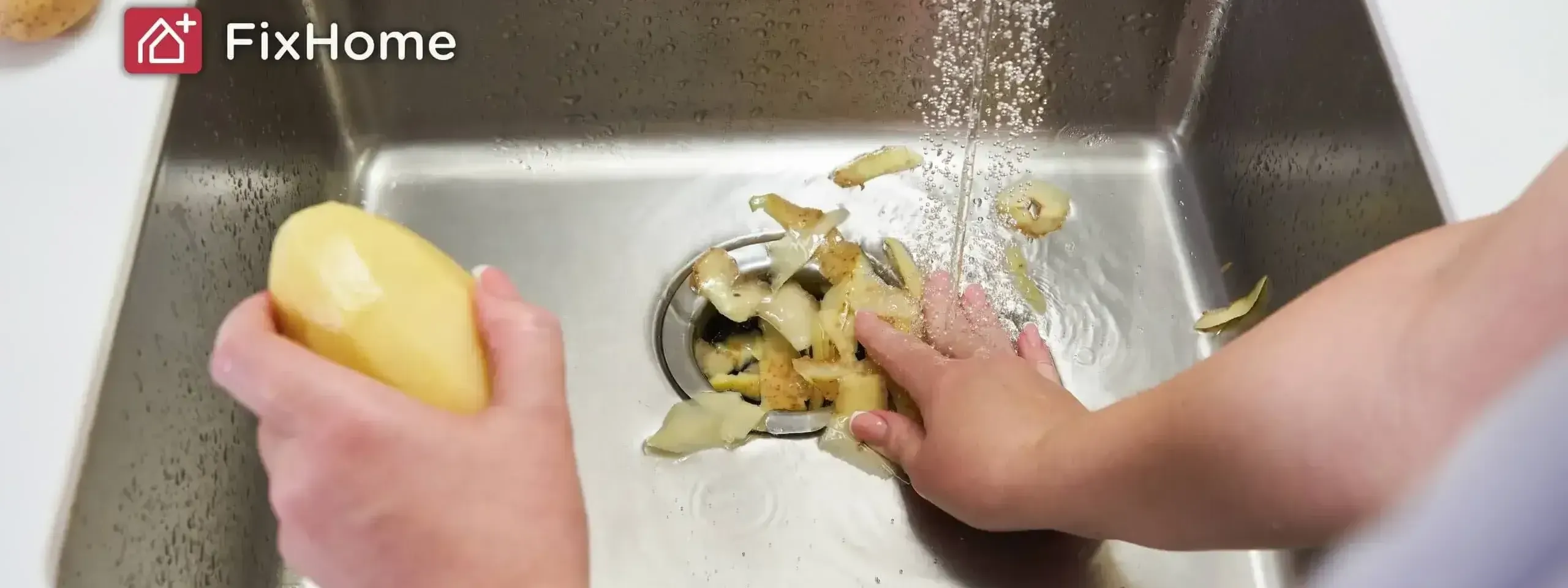 Hands pushing potato peels into a garbage disposal while water runs.