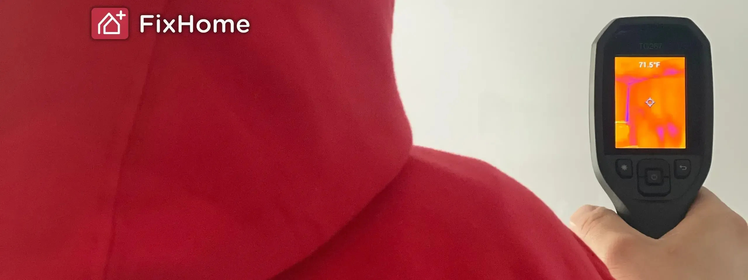 A person in a red hoodie using a thermal camera to inspect a wall