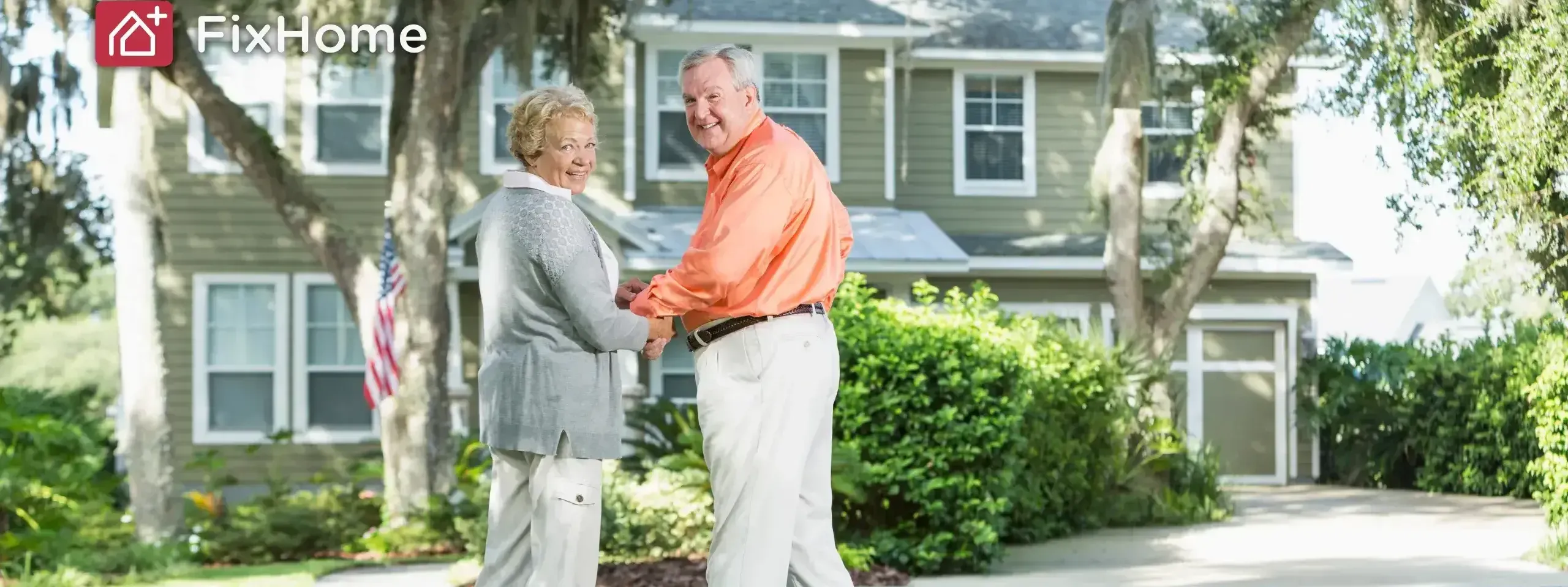 A senior couple happily holding hands in front of their home