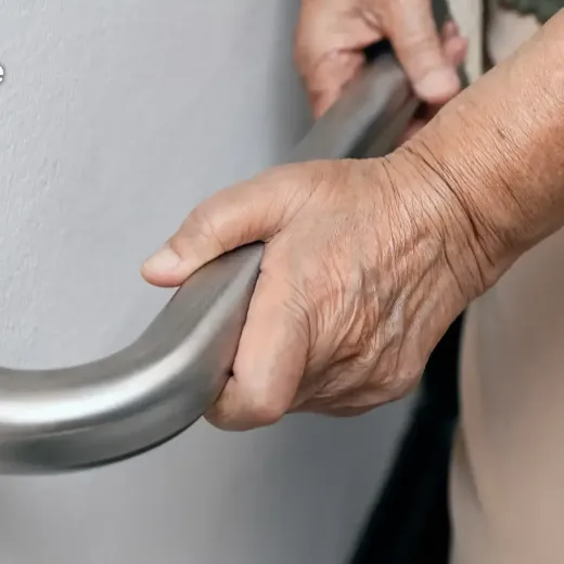 A close up of a hand holding a metal grab bar 