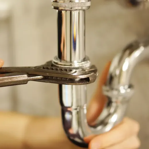 Plumber fixing a under sink pipes with a wrench