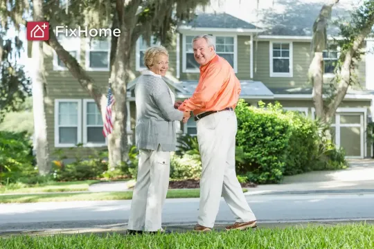 A senior couple happily holding hands in front of their home