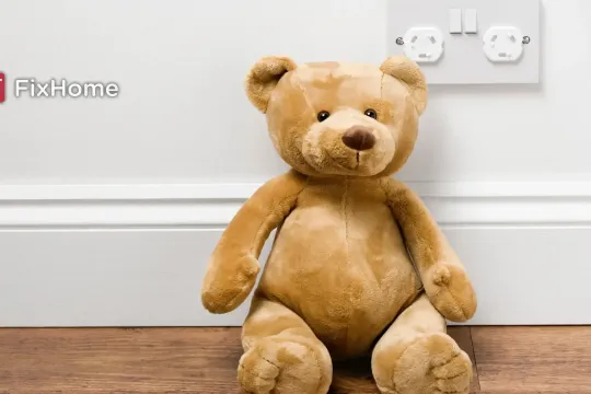 Teddy bear next to a outlet with closed protective covers