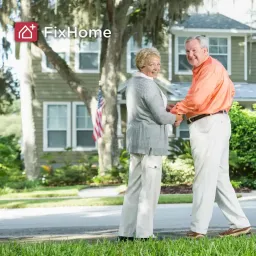 A senior couple happily holding hands in front of their home